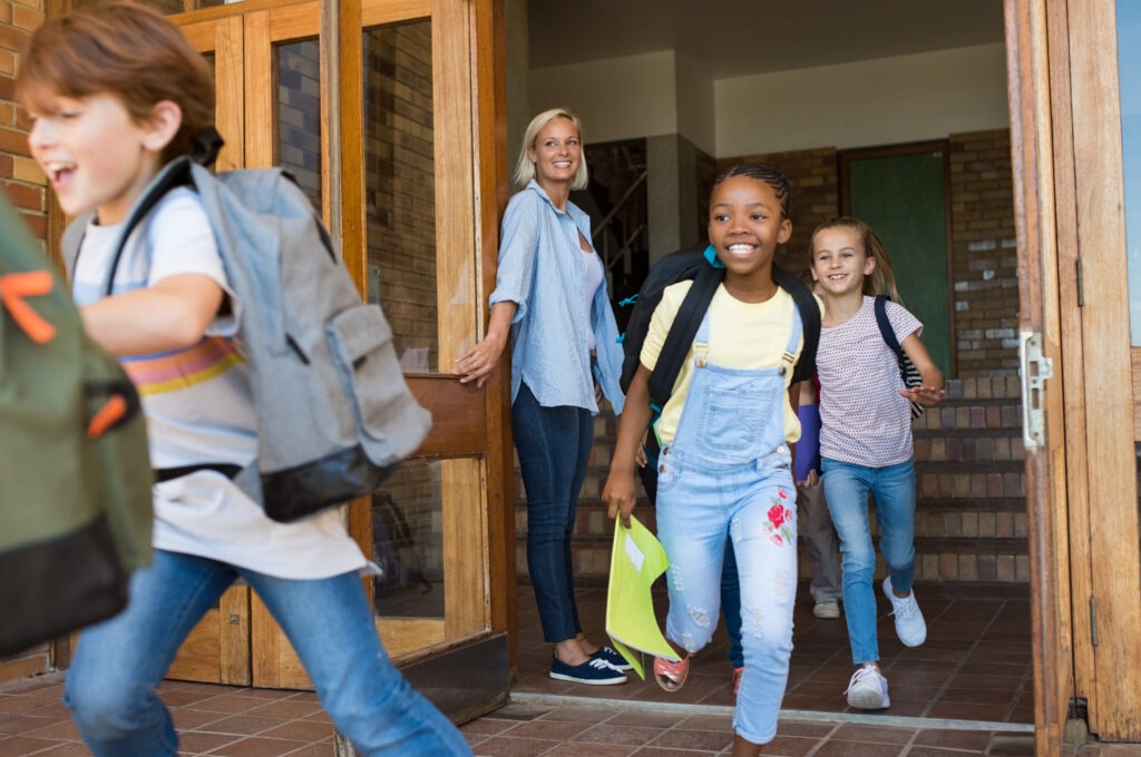 Group of Elementary School Children Running Outside at the End of the Lessons